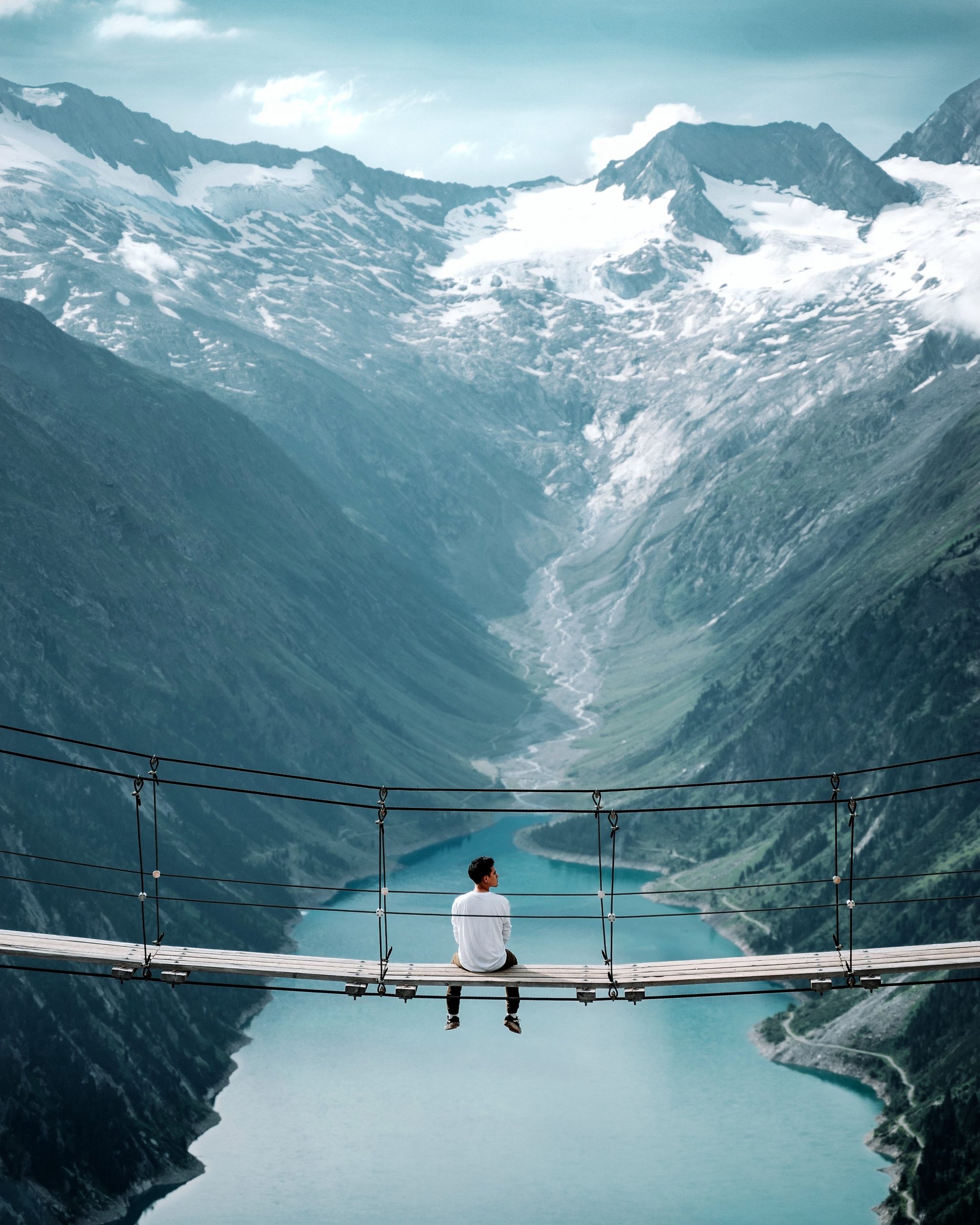 a man sitting on a bridge over a river