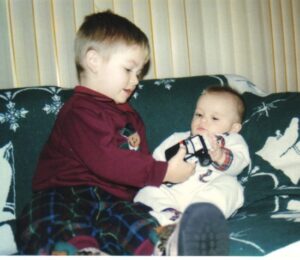 a toddler showing an infant his toy truck