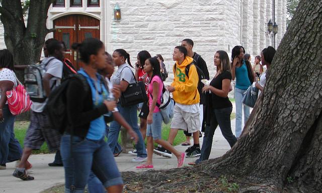 Photo of Students walking on a busy sidewalk on a college campus